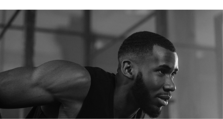 Man i träningsposition, svartvitt foto, ser fokuserad ut.