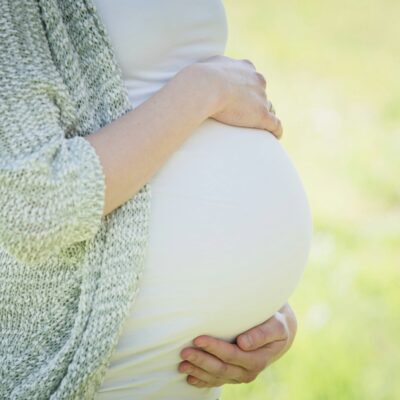 Gravid kvinna som håller händerna på magen